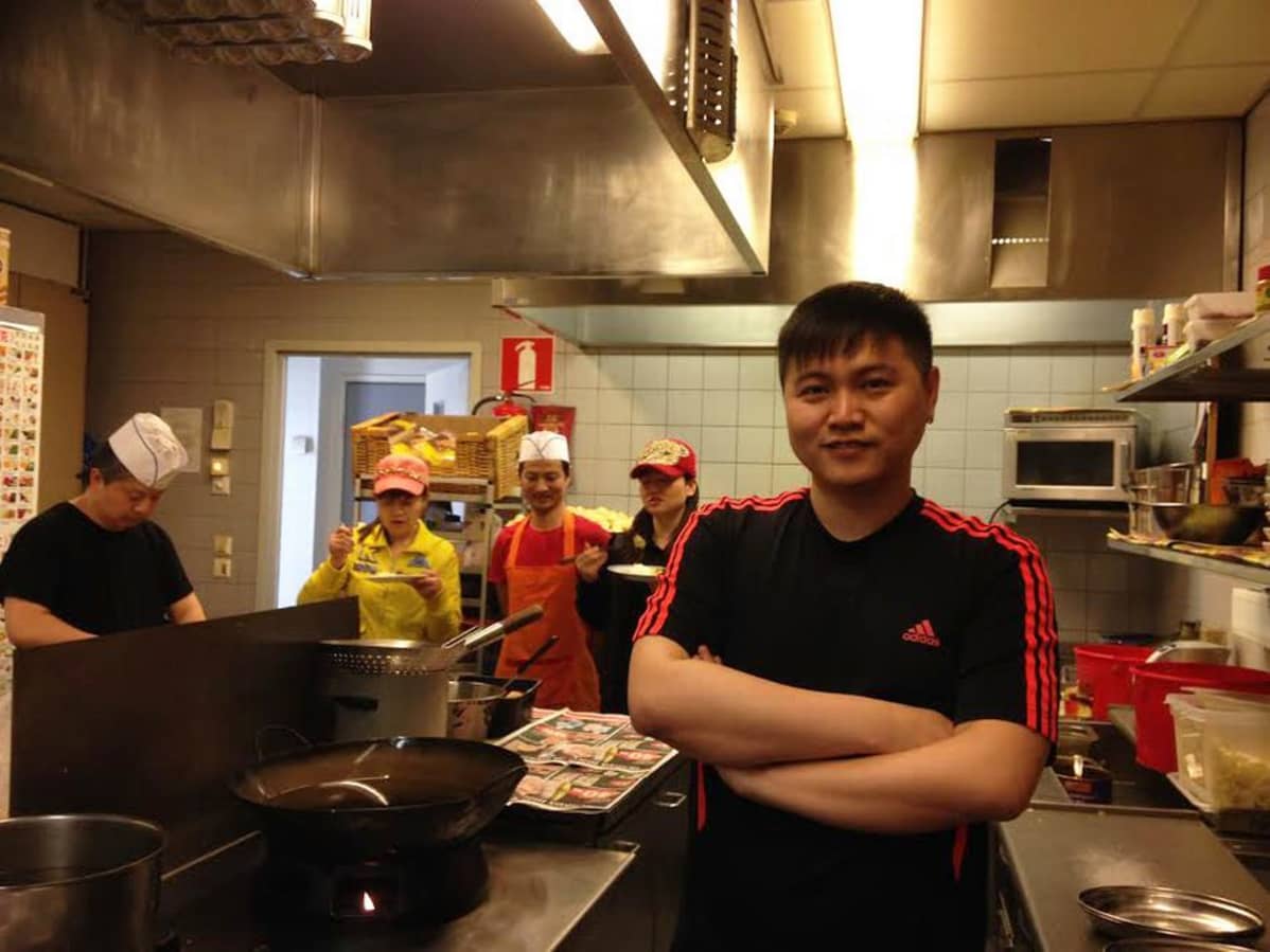 Kajaanissa kiinalaista ravintolaa pyörittävä Li Biao seisoo ravintolansa keittiössä, taustalla tuttuja ja henkilökuntaa.