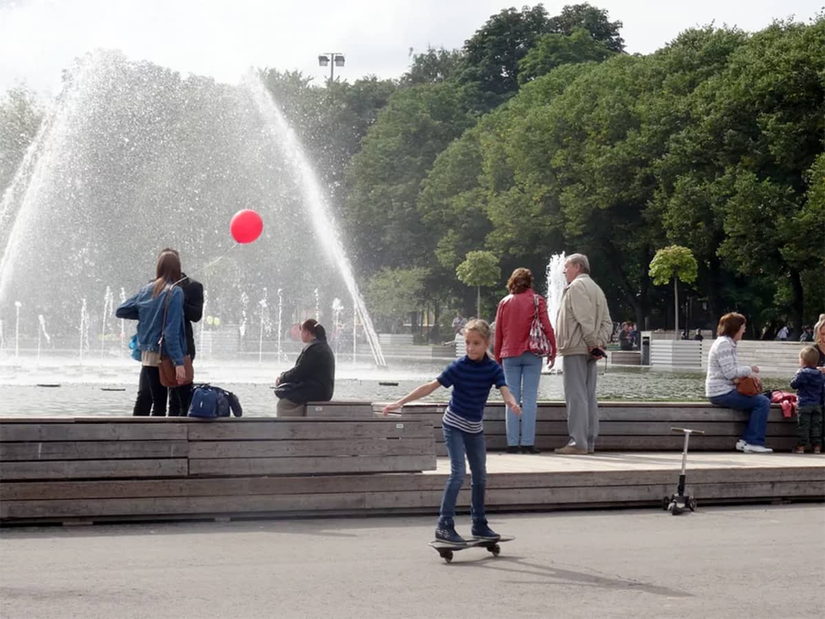 suihkulähde puistossa ja rullalautaileva tyttö