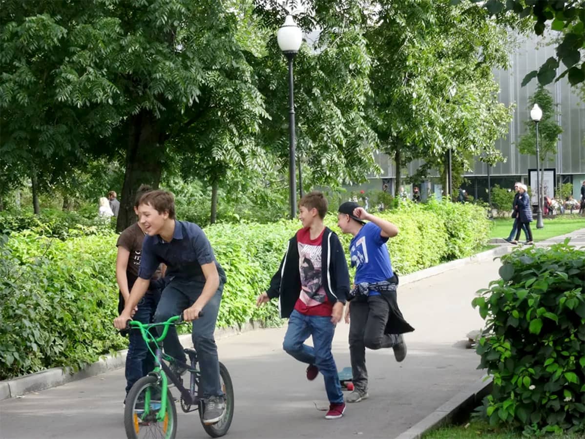 puistossa juoksevia poikia, yksi pyöräilee