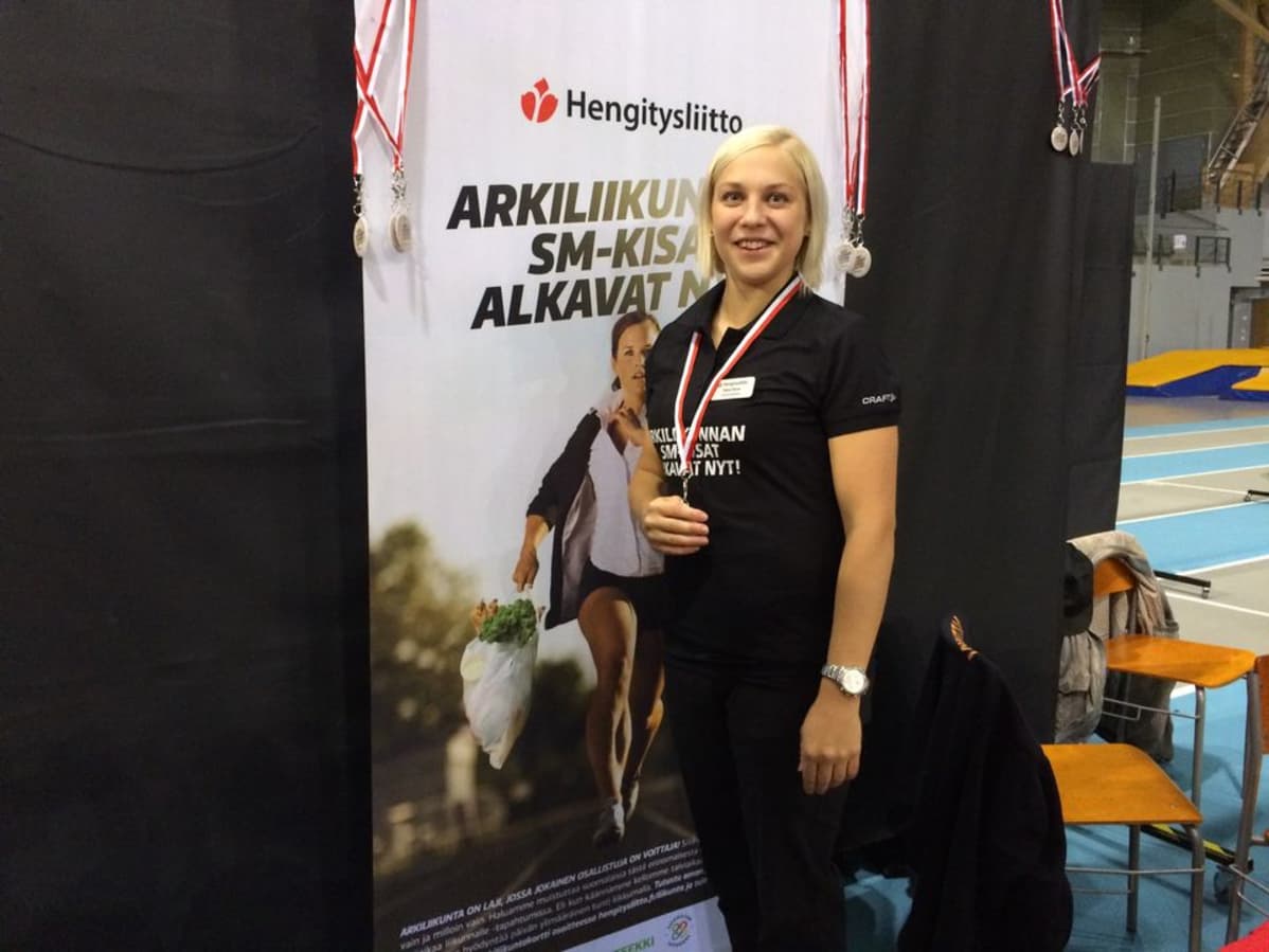 Nainen seisoo julisteen edessä ja kampanjoi arkiliikunnan puolesta.