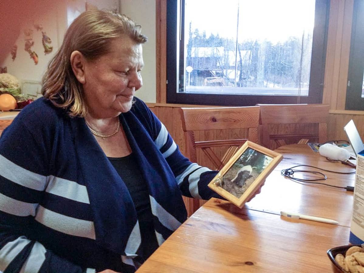 nainen pitelee possunkuvaa kädessään