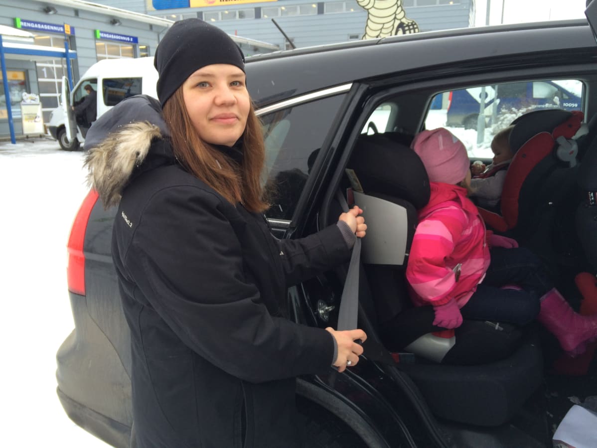nuori nainen laittaa lapsia autoon
