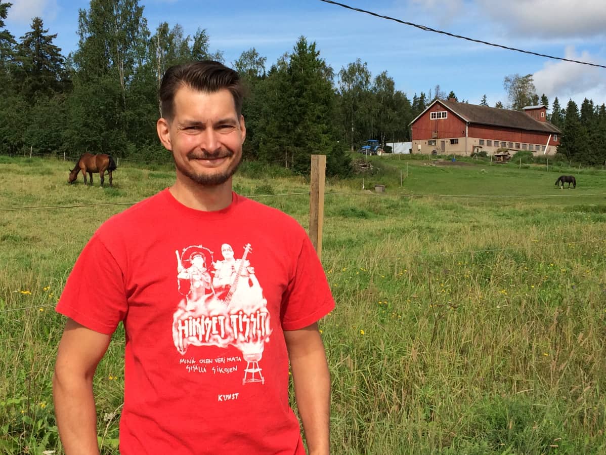 Mies maatilan hevoslaitumen edessä