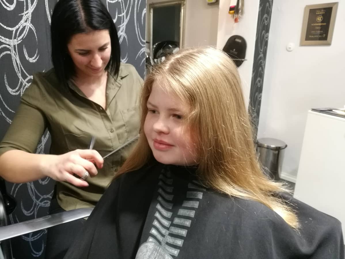 Neria Oranta istuu parturi-kampaaja Jonna viljasen asiakkaana.