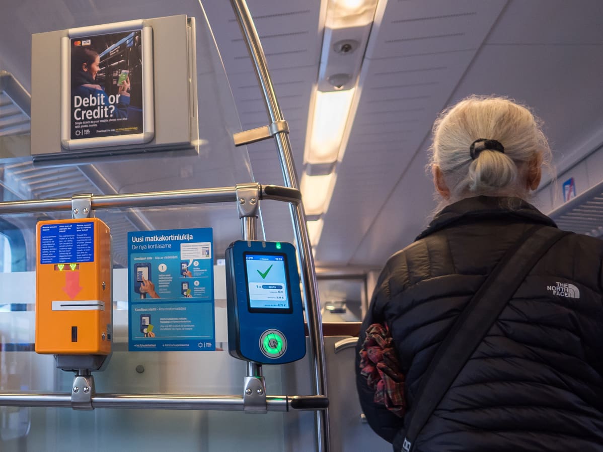 Nainen luki matkakorttinsa astuessaan junaan.