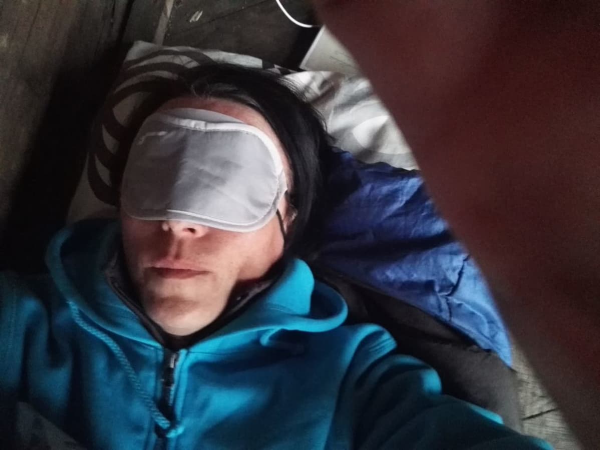 Toimittaja nukkuu laavulla silmillä laput.