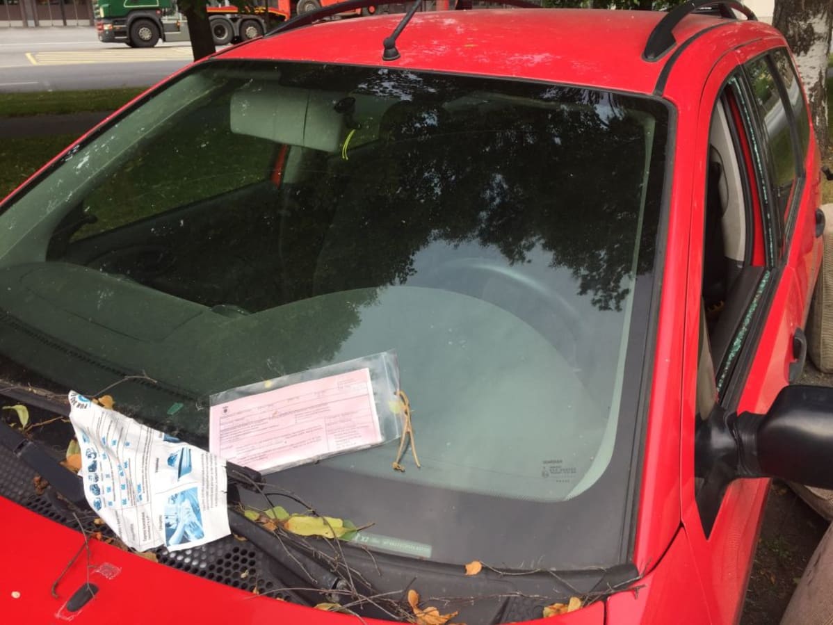 Hylätty auto poliisilaitoksen parkkipaikalla.