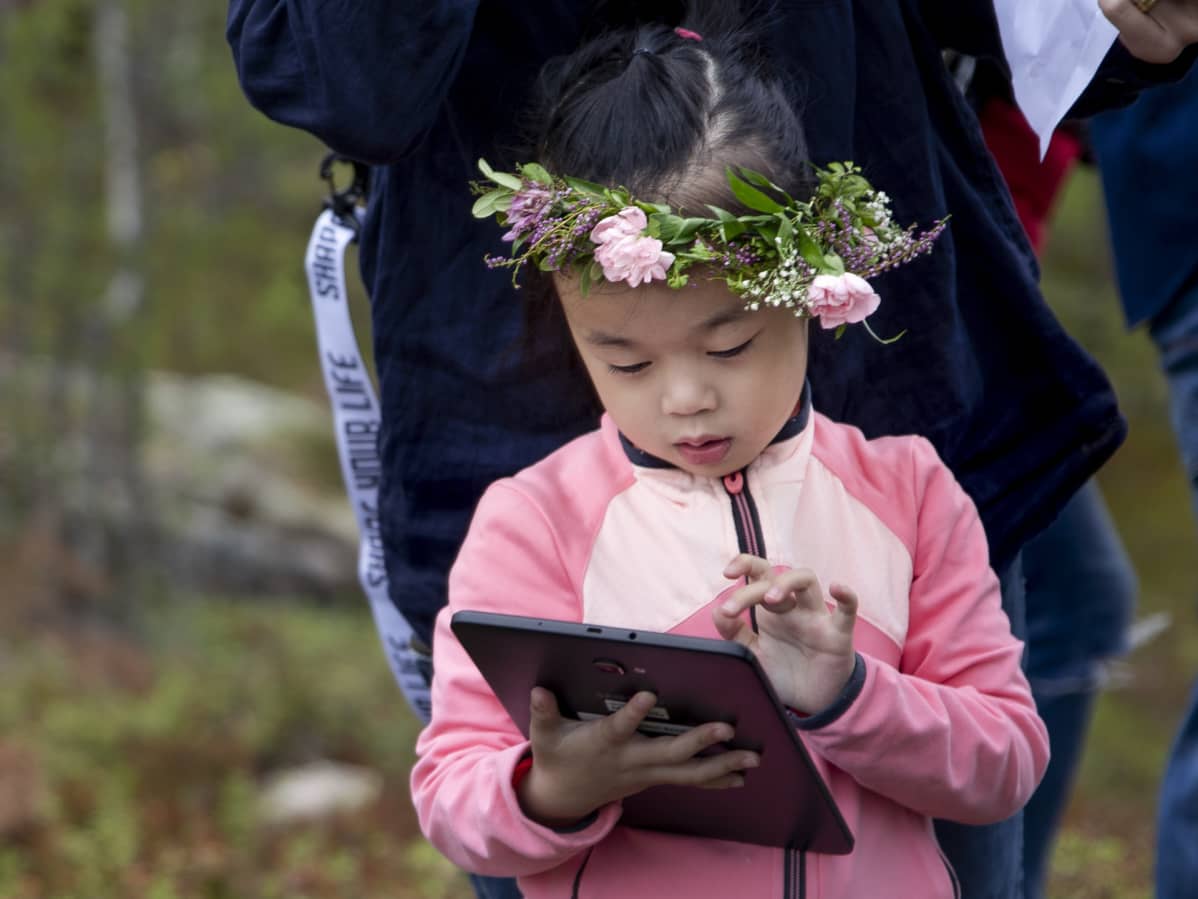 Kiinalainen tyttö katsoo tablettia.