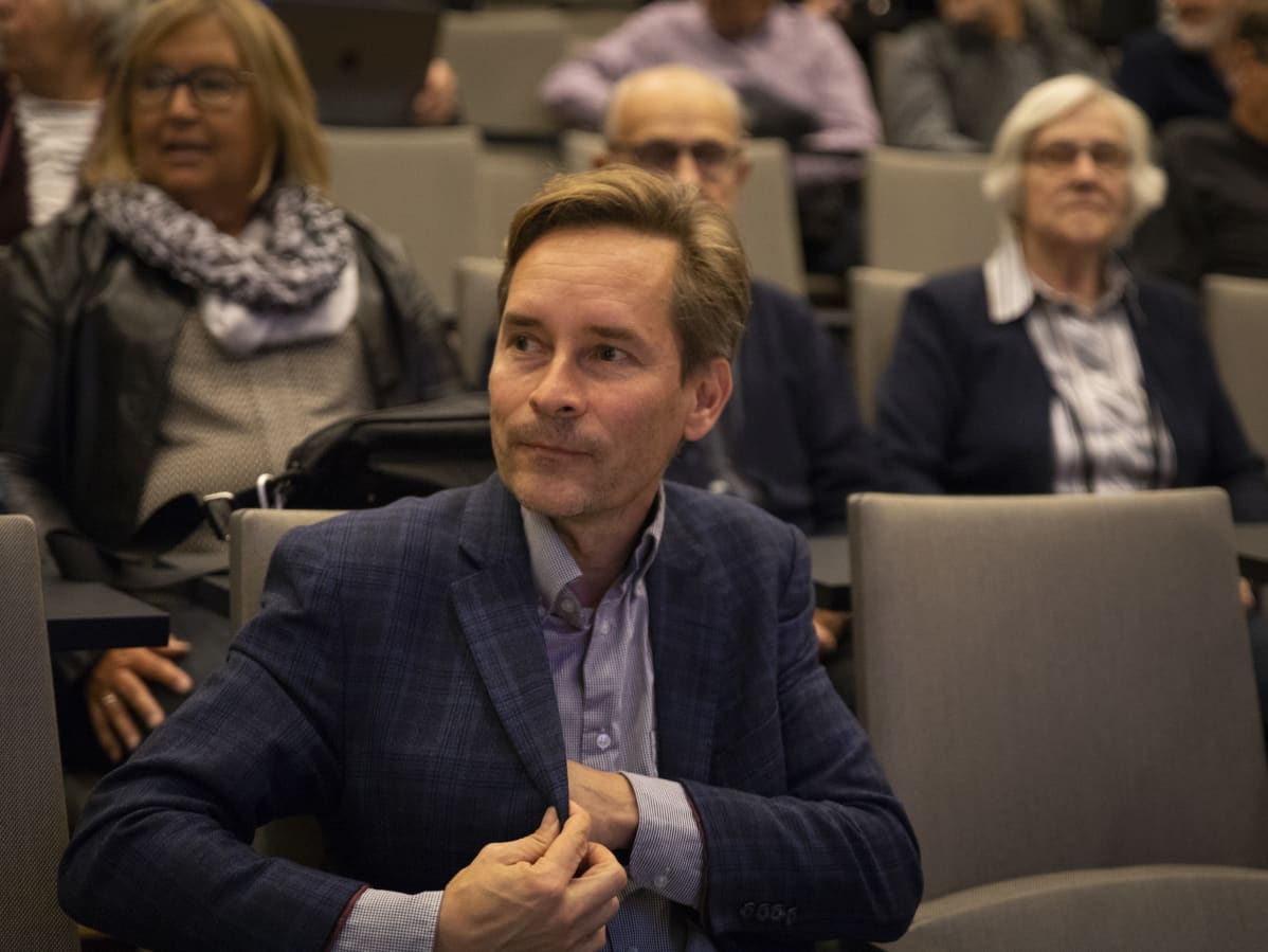 Mies kaivaa taskuaan auditoriossa.