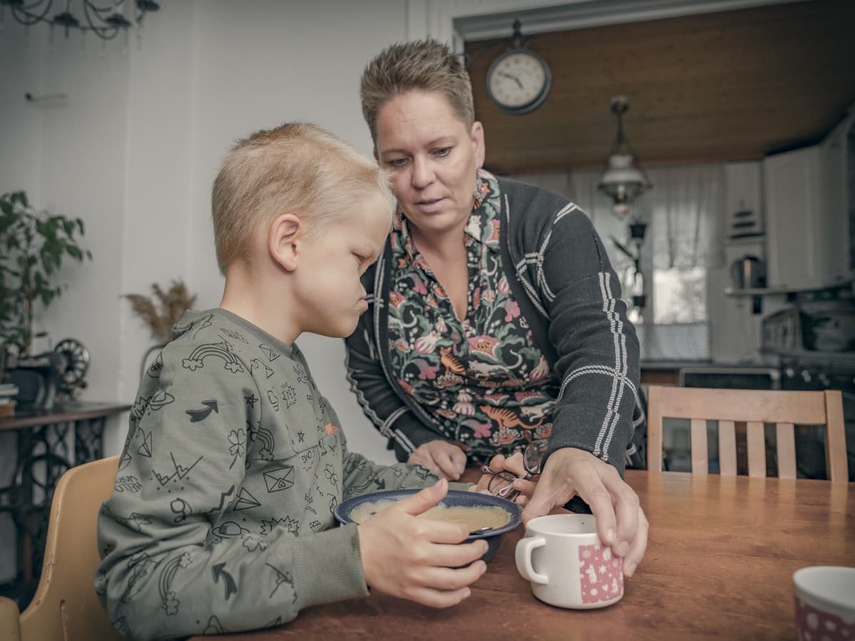 Äiti ja poika syövät pöydän ääressä
