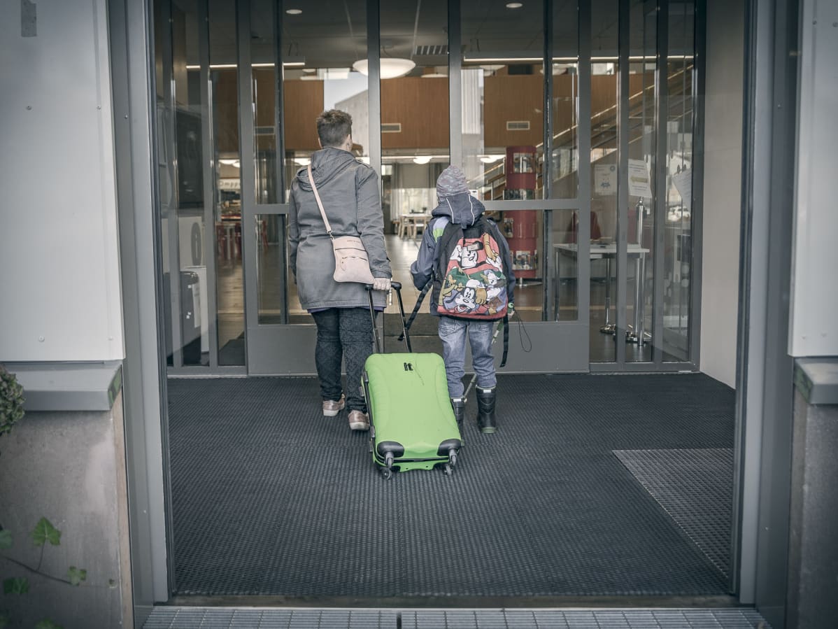 Äiti ja poika vetävät matkalaukkua