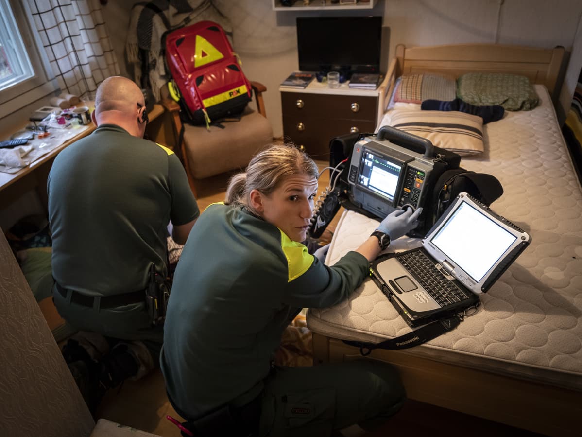 Ambulanssin henkilökuntaa vanhuksen makuuhuoneessa.