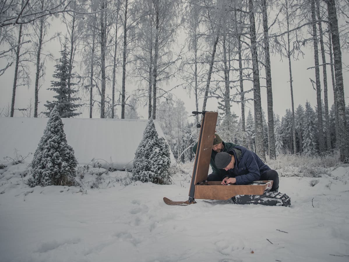 Miehet korjaavat sähkölumiskootteria.