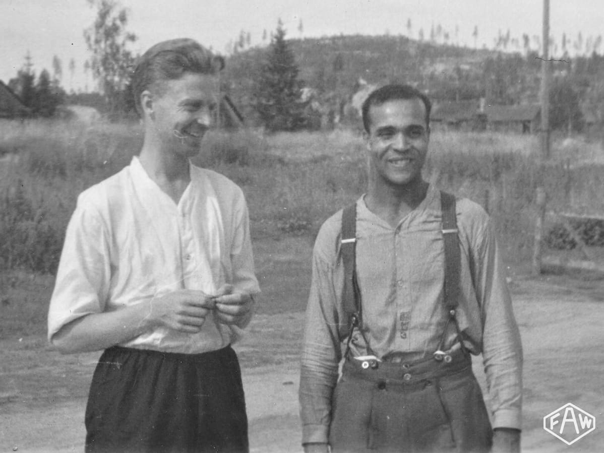 Holger Sonntag hymyilee siviilivaatteissa, vieressä toinen mies joka katsoo Sonntagia.