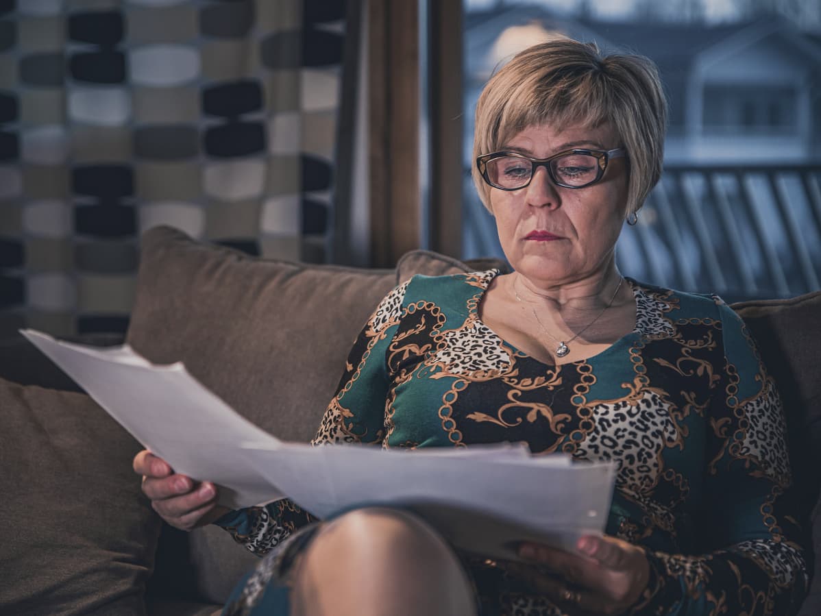 Päivi Varakas lukee papereita sohvalla istuessaan.
