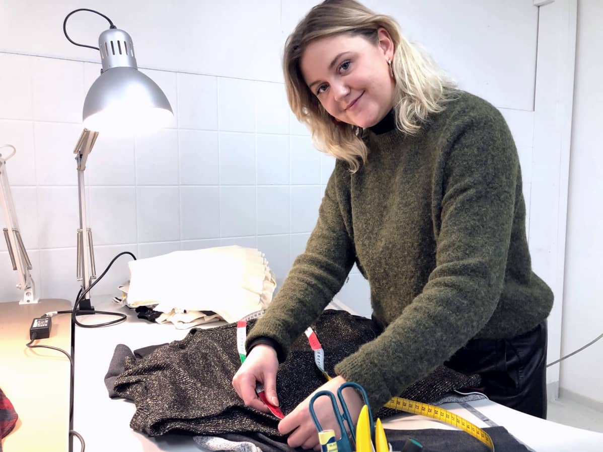 Nainen mittaa vaatteen koon mittanauhalla.
