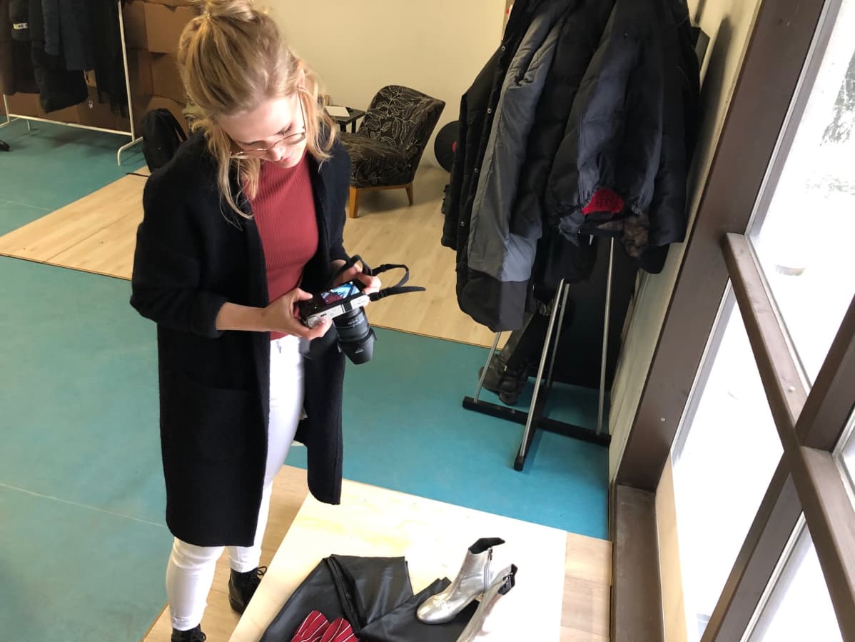 Nainen valokuvaa vaatteita vanerialustalla.