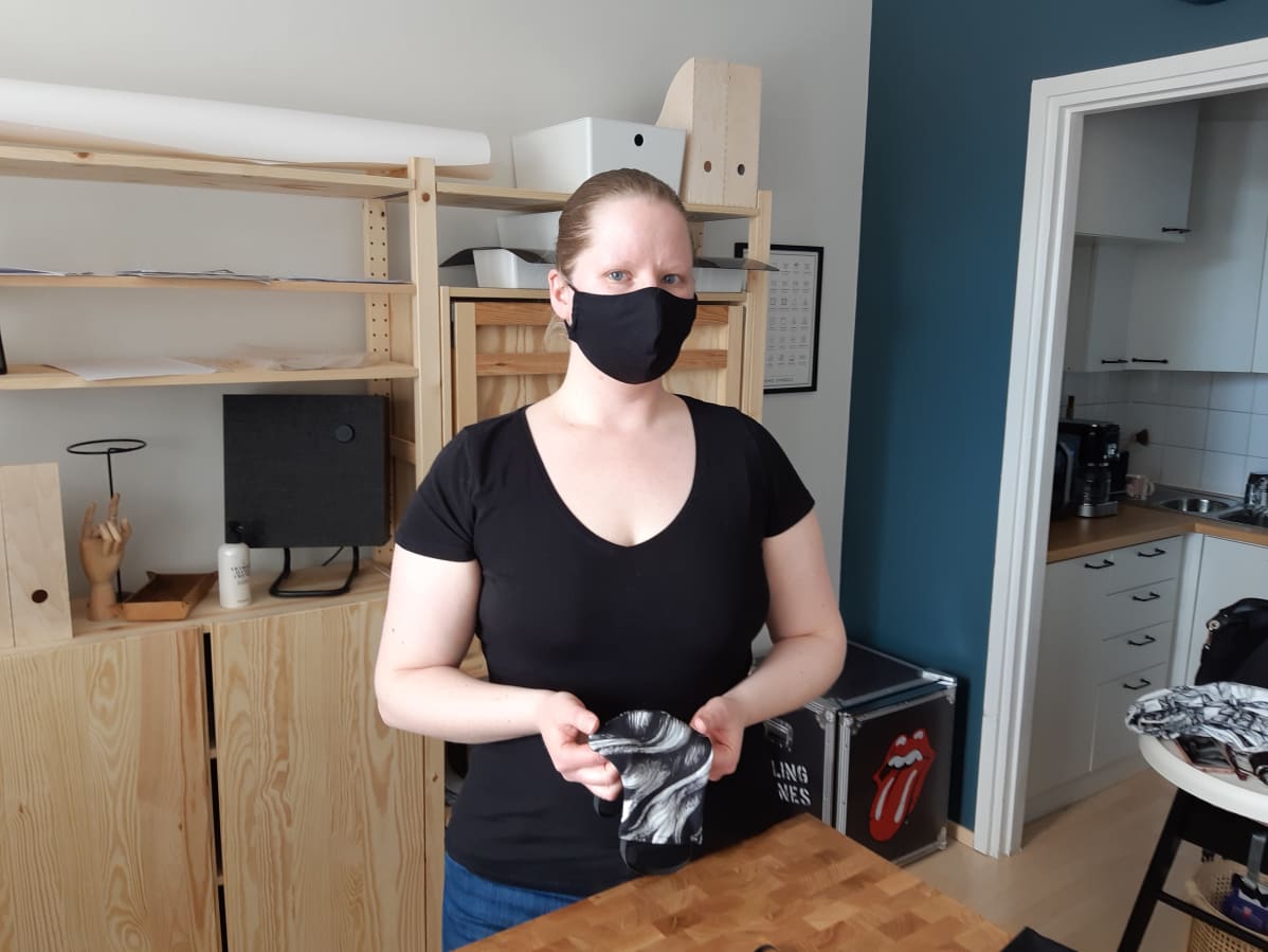Maria Ravea tekemänsä kasvomaski kasvoillaan, toinen kädessään.