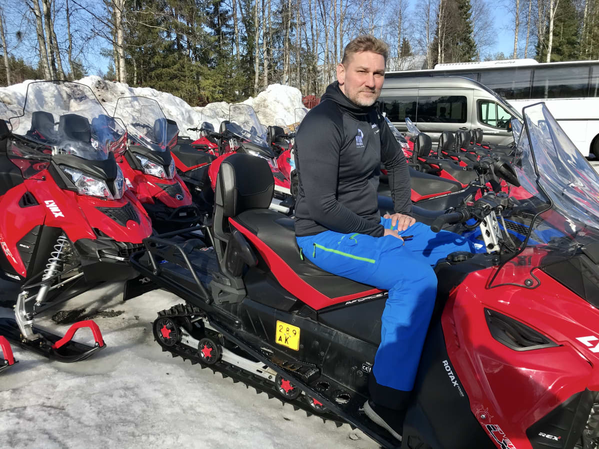 Rovaniemeläinen matkailuyrittäjä Sami Päivike safariyrityksensä moottorikelkkojen keskellä