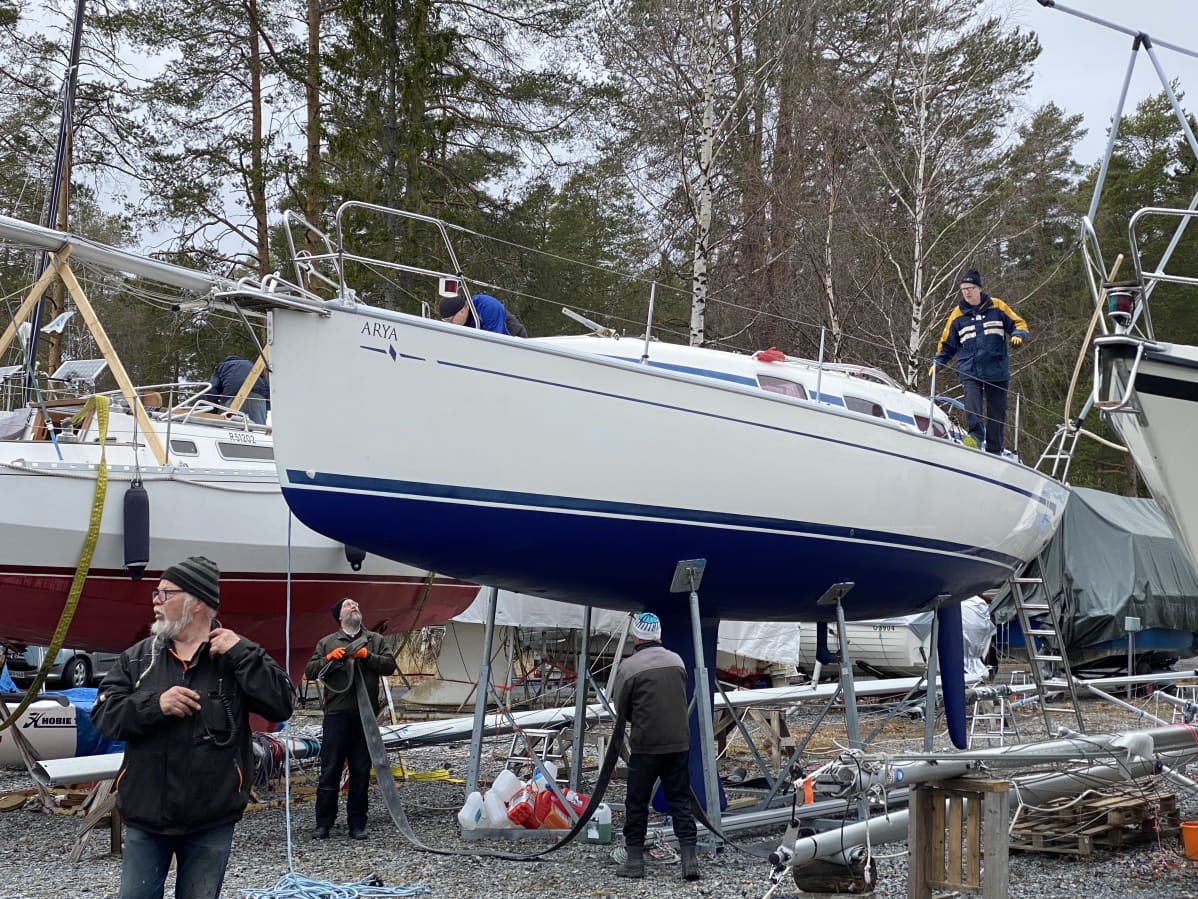 Ihmiset laittavat liinoja veneeseen nostoa varten.