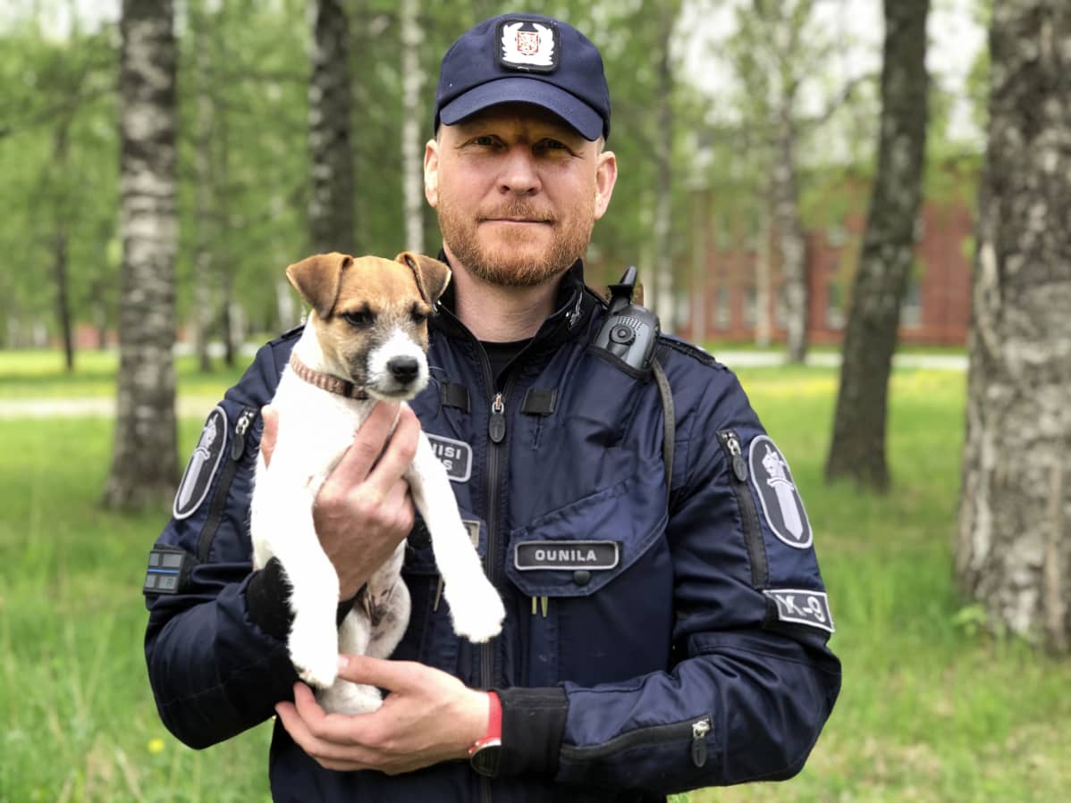 Vanhempi konstaapeli Miikka Ounilan sylissä poliisikoiranpentu Patrik