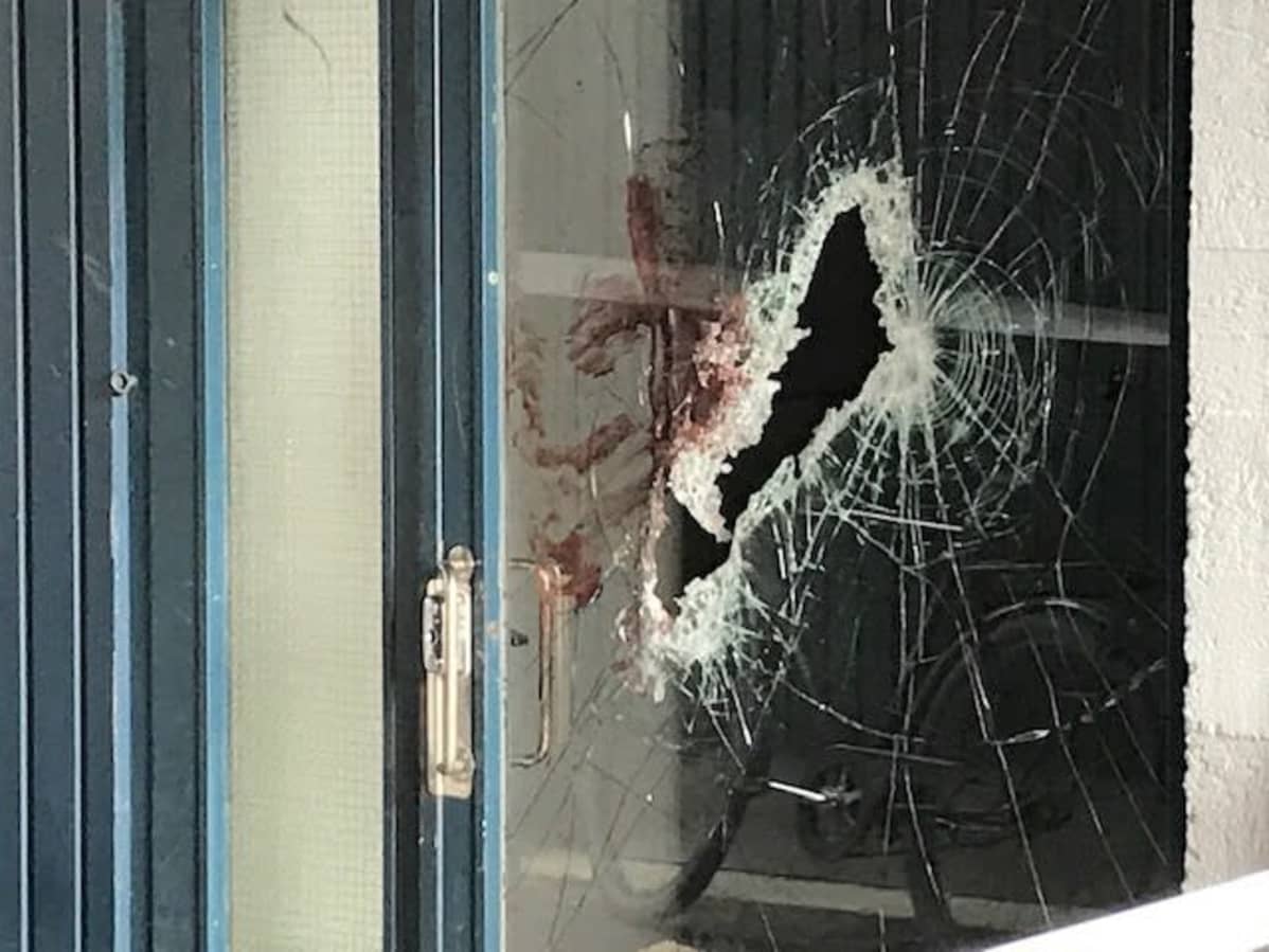 Kuva rikkinäisestä ja verisestä kerrostalon lasiovesta