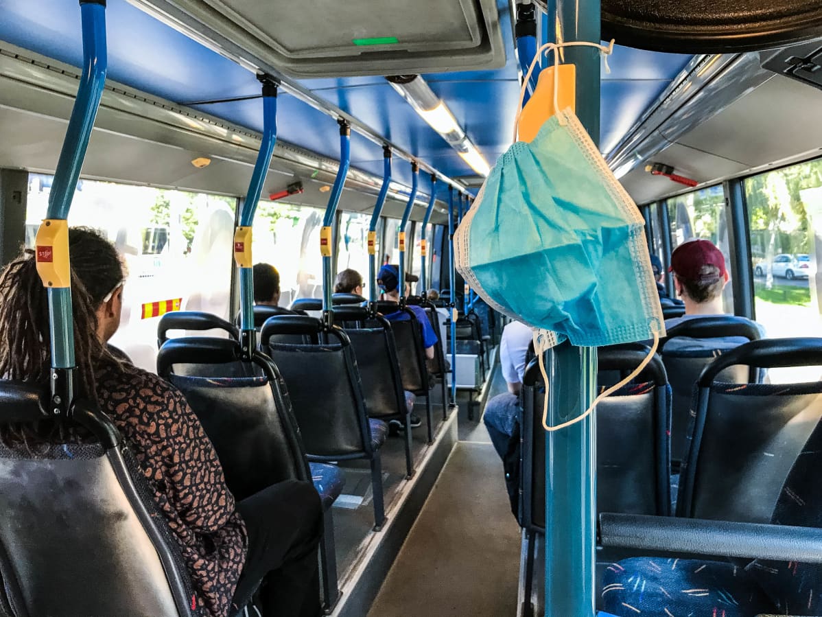 Hengityssuojain roikkuu bussissa.