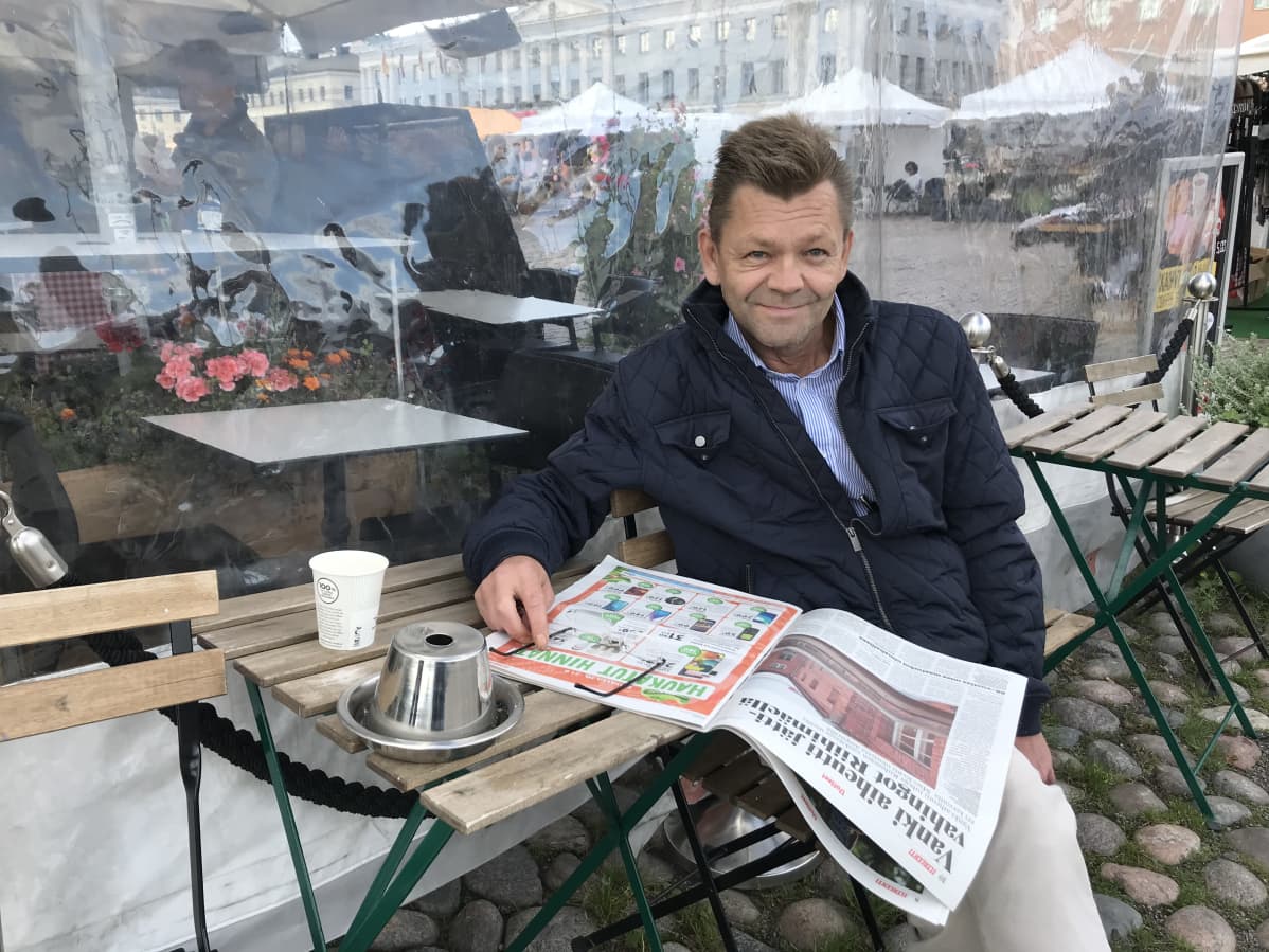 Mika Grönblad lukee lehteä torikahvilassa.