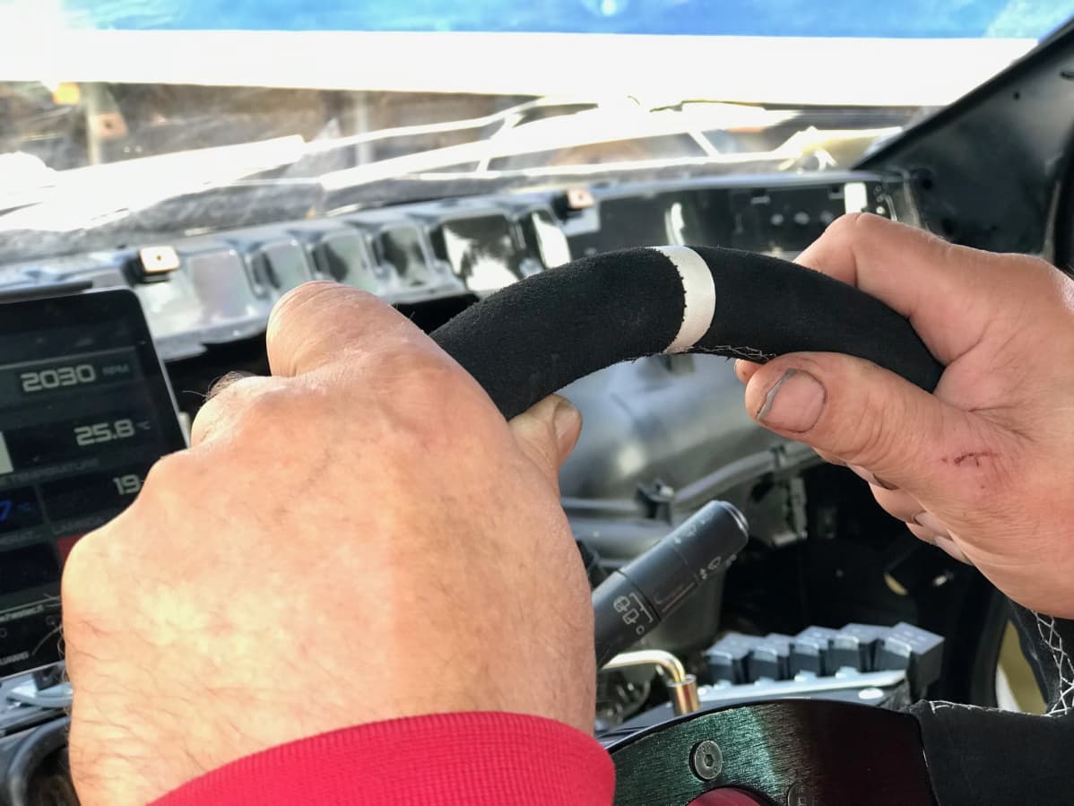 Miehen kädet pitävät kiinni ralliauton ratista
