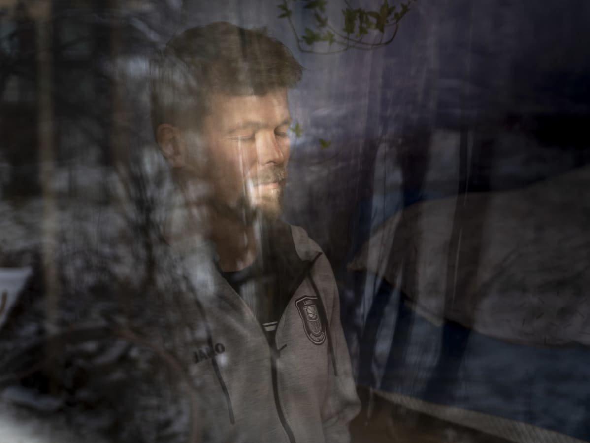 Koripallovalmentaja Pieti Poikola meditoi. Kuva otettu ikkunan läpi.