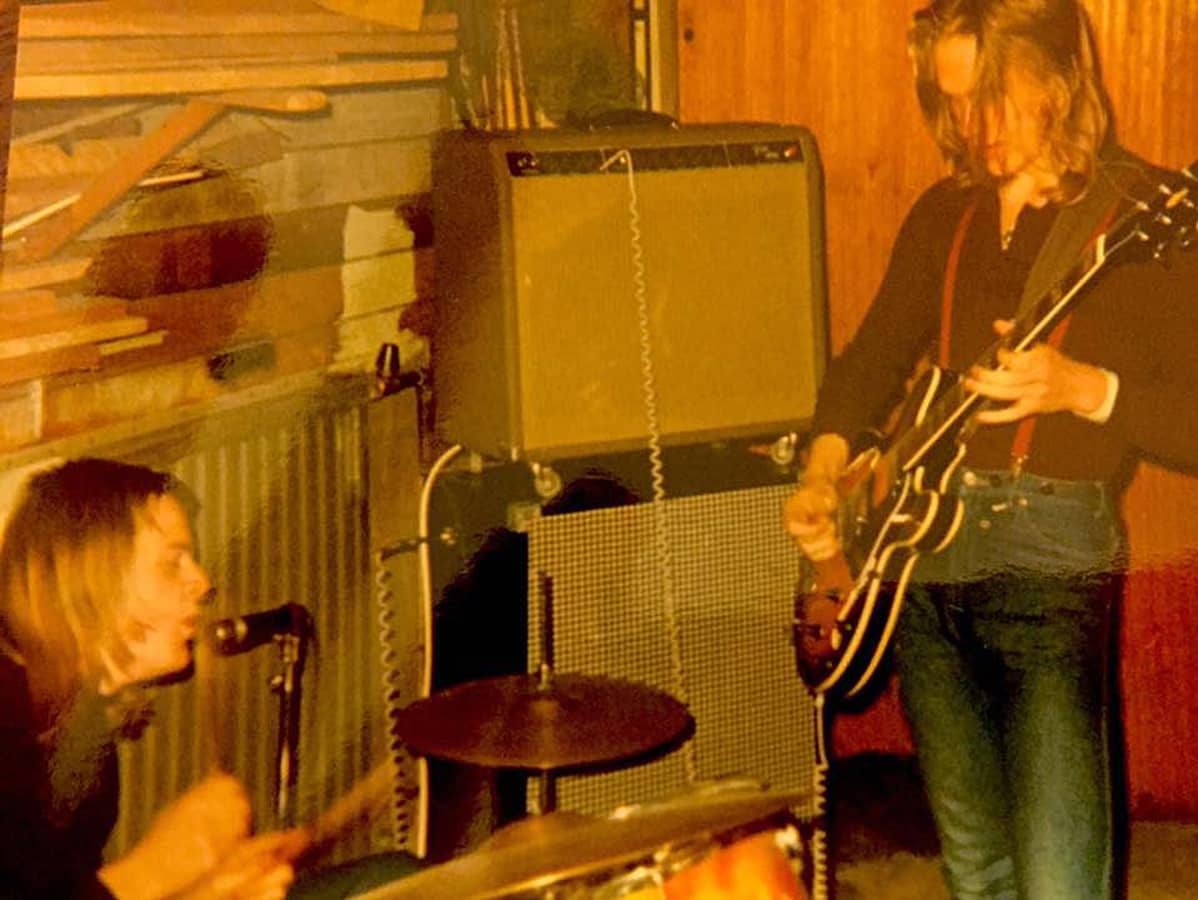 1970-luvun alku, bändin kaksi jäsentä soittaa vanhassa valokuvassa, Pelle Miljoona rummut, Hapa Tyni, kitara
