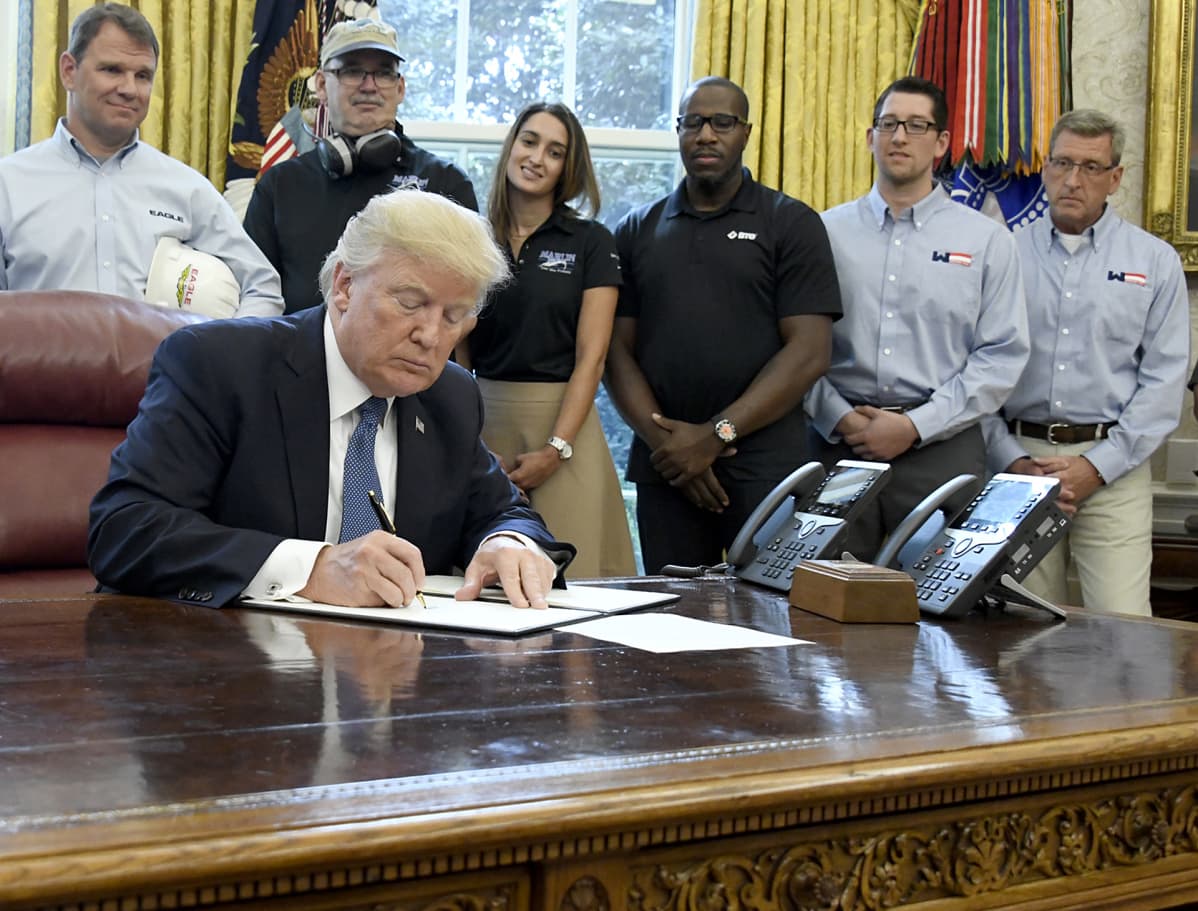 Presidentti Donal Trump allekirjoittaa.