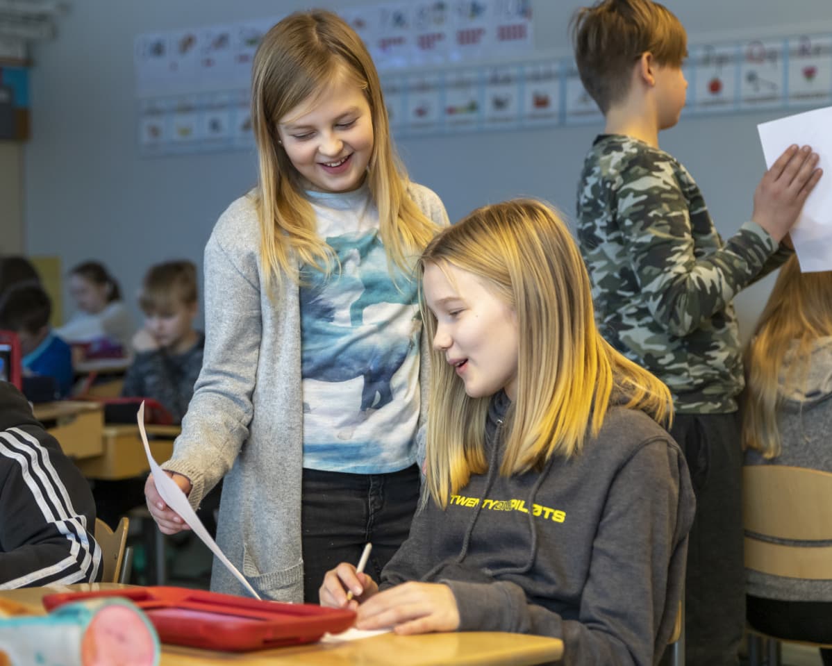 Nea esittelee Iidamarialle tekemäänsä piirrosta kuvaamataidon tunnilla.