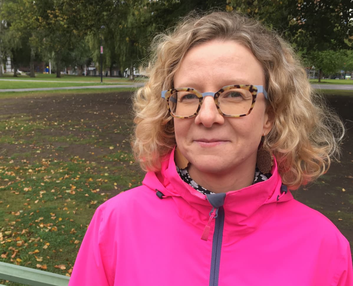 Tutkijatohtori Nina V. Nygren seisoo puistossa punaisessa takissa.