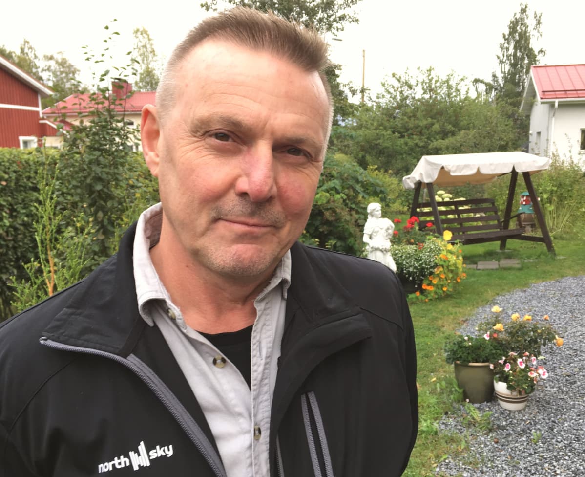 Timo Lehtonen seisoo puutarhansa edustalla.