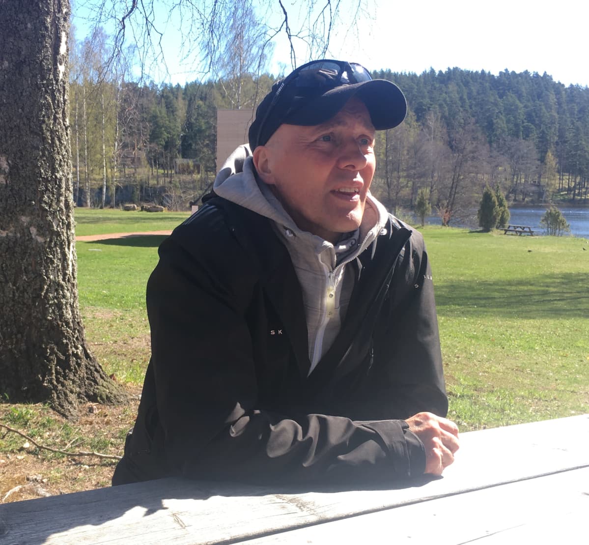 Juha Seittonen "Quuppa" istuu puupöydän ääressä ulkona