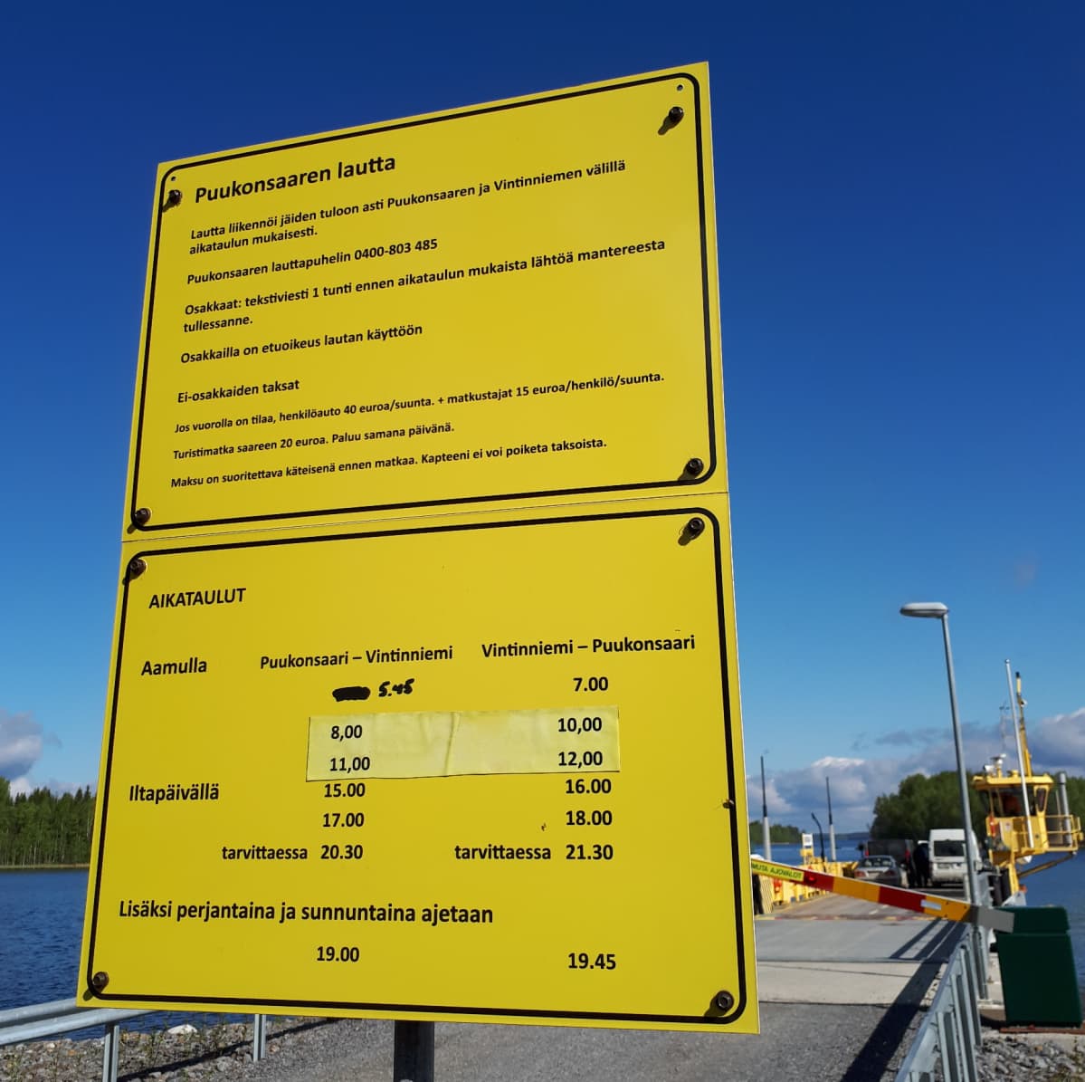Keltainen kyltti, joka kertoo Puukonsaaren lautan aikataulut.