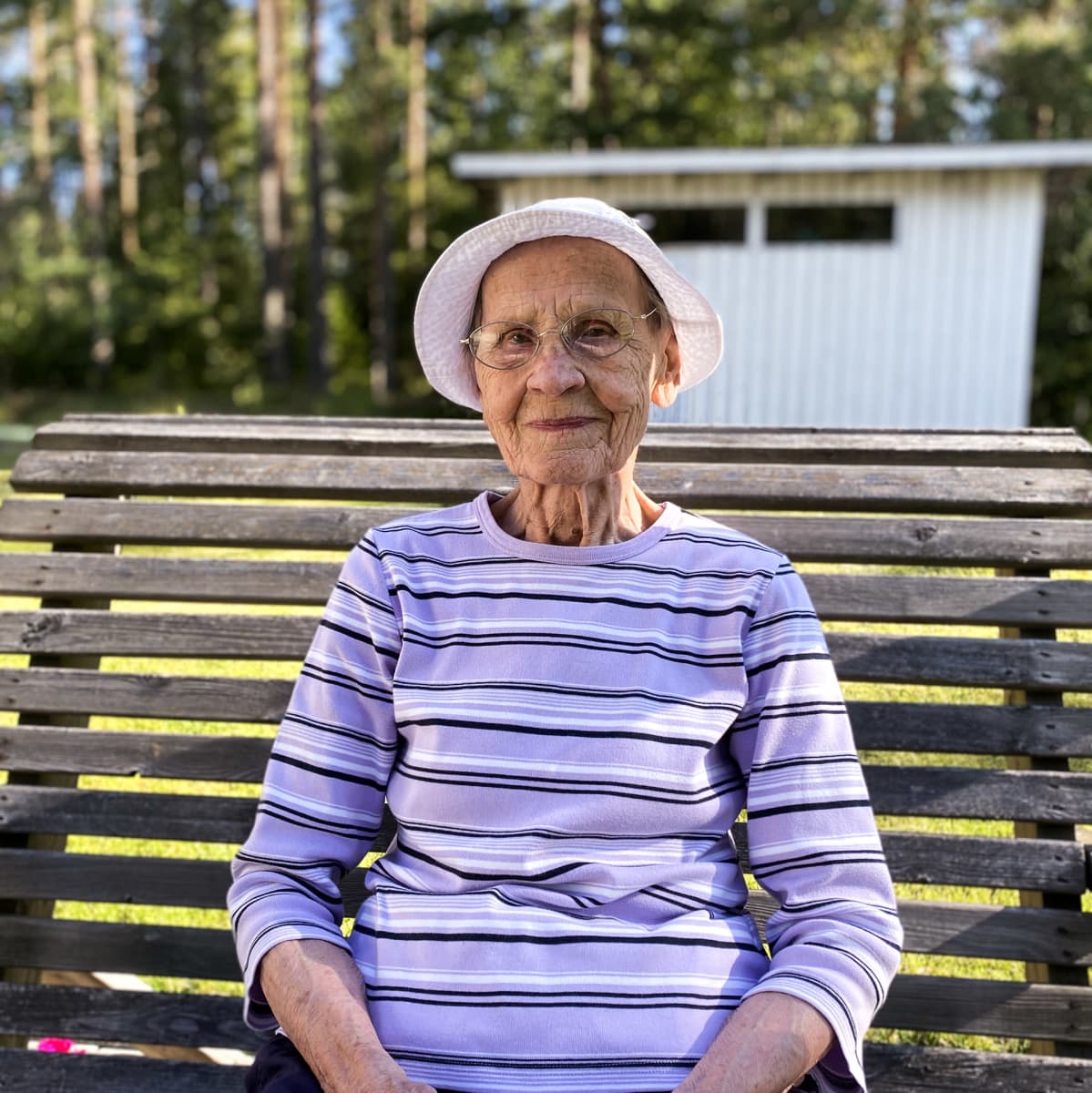 Elsa Pekkala 91 vuotta istuu kotipihassaan keinussa.