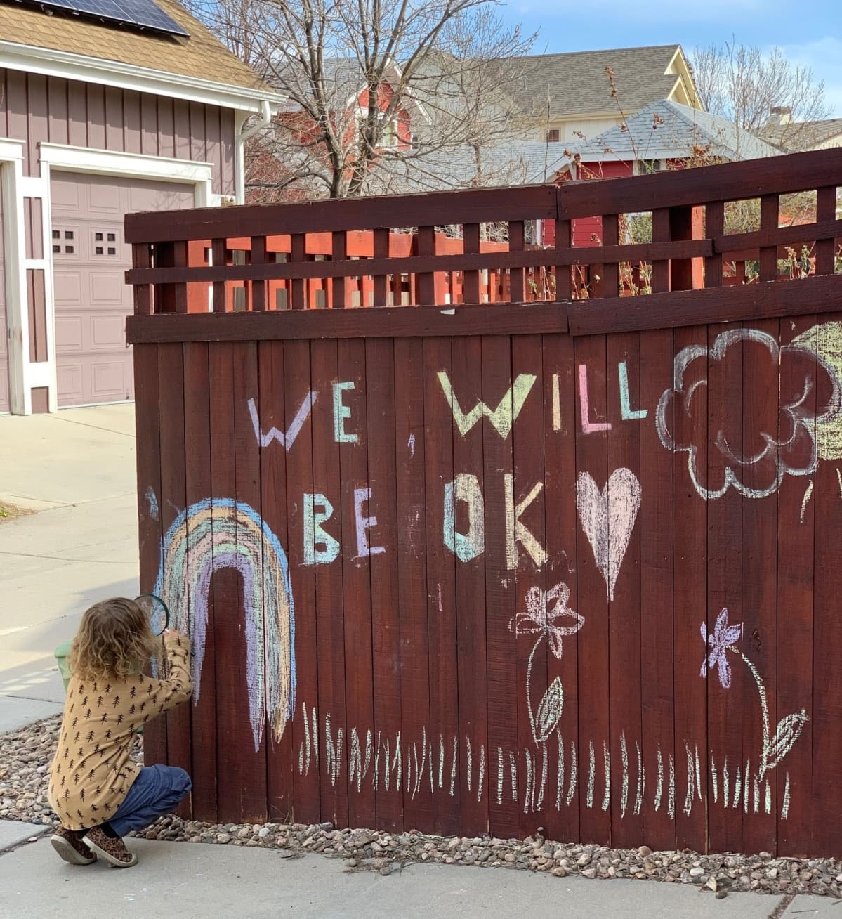Lapsi piirtää aitaan "We will be OK"