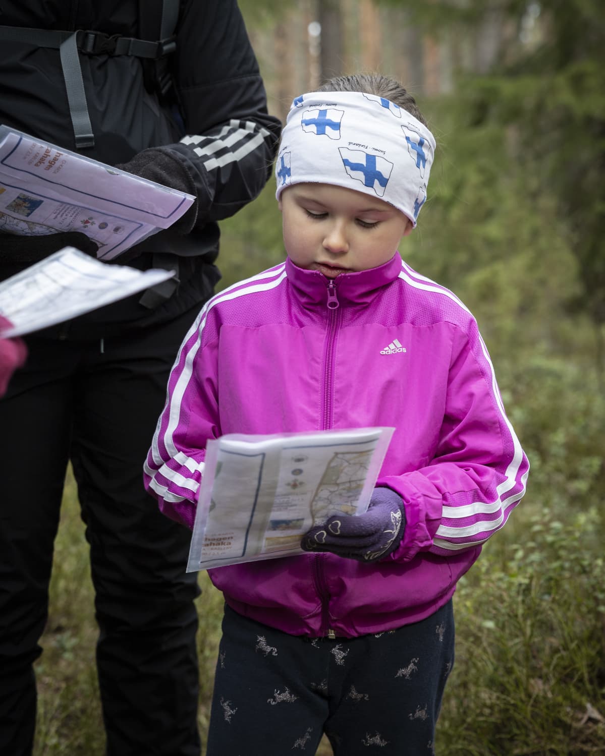 Minea Vanhala tutkii karttaa metsässä.