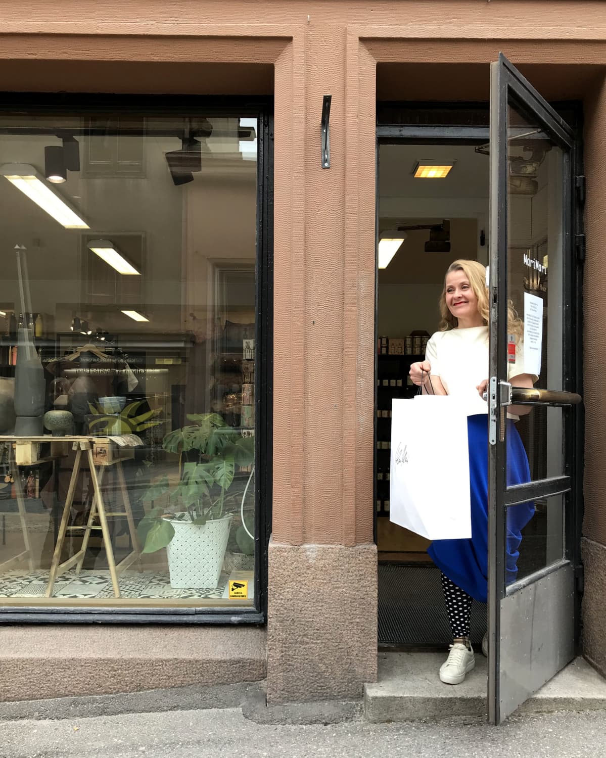 yrittäjä Mari Nieminen ojentaa paperipussin oven suusta