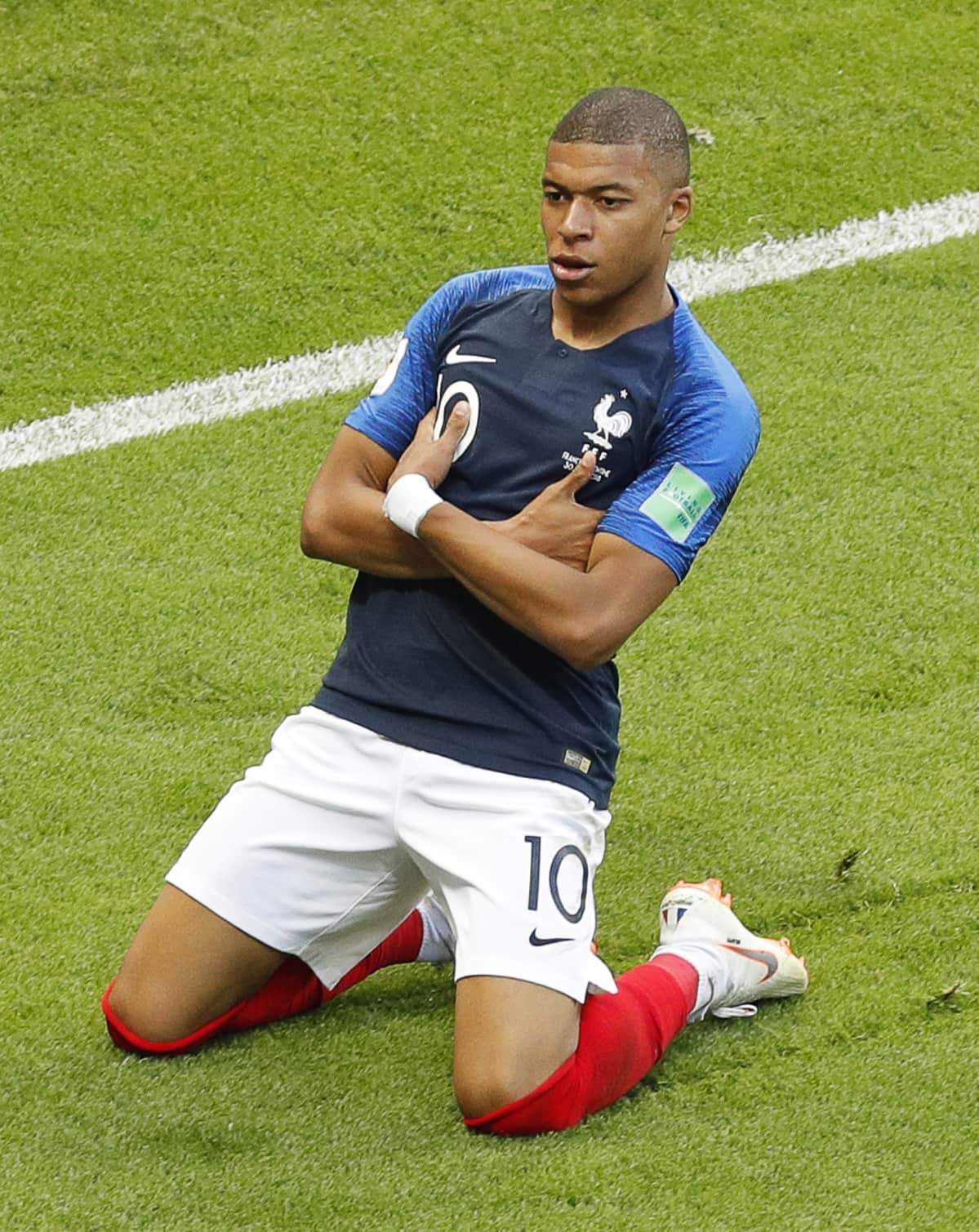 Kylian Mbappe tuulettaa polvillaan maalia.