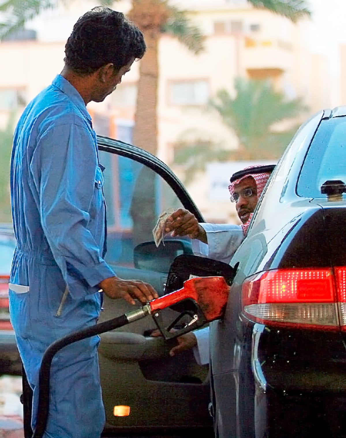 Saudimies maksaa huoltoasemalla autonsa tankkauksesta.