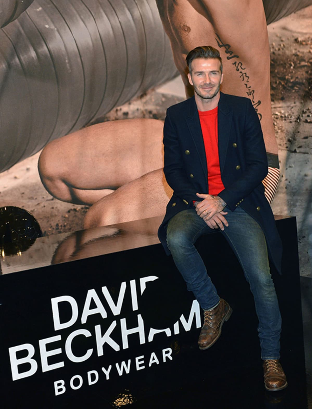 David Beckham poseeraa nimikkomallistonsa mainosjulisteständin edessä.
