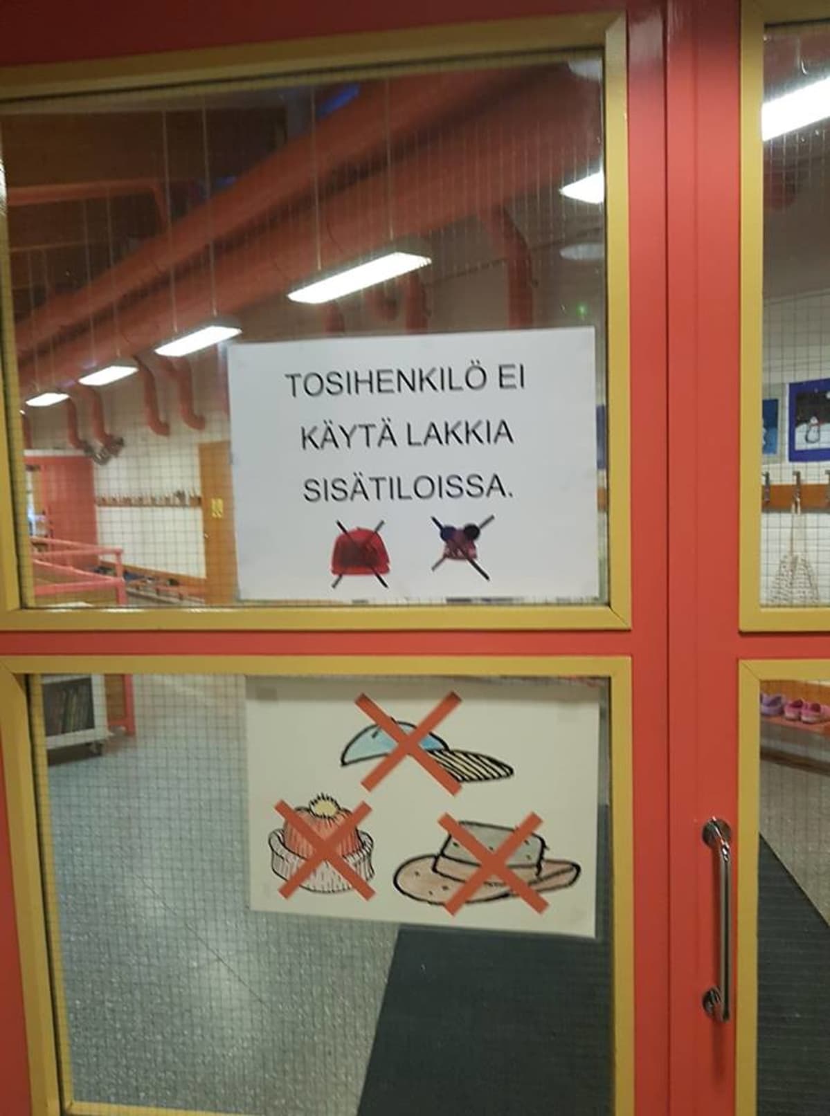 Tosihenkilö ei käytä lakkia sisätiloissa sanotaan koulun kyltissä.