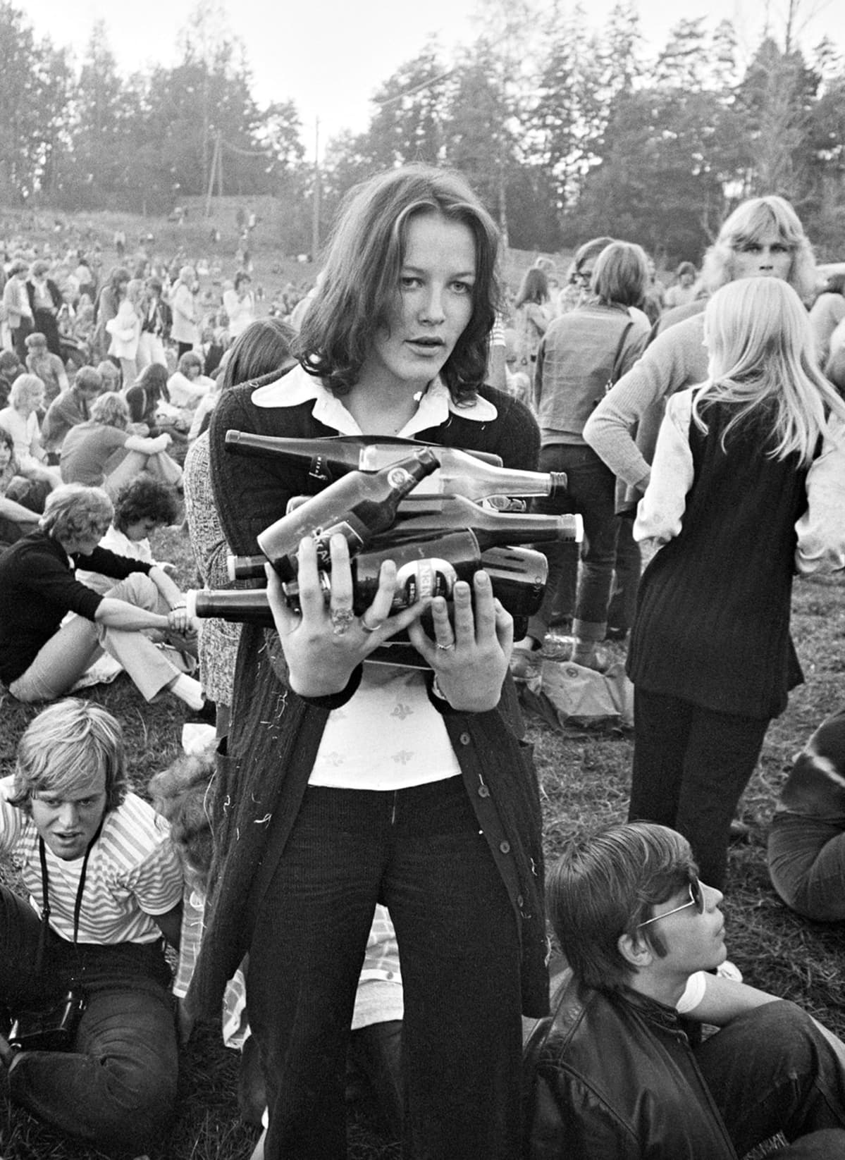 Nainen kantaa tyhjiä pulloja Ruisrockissa 1970