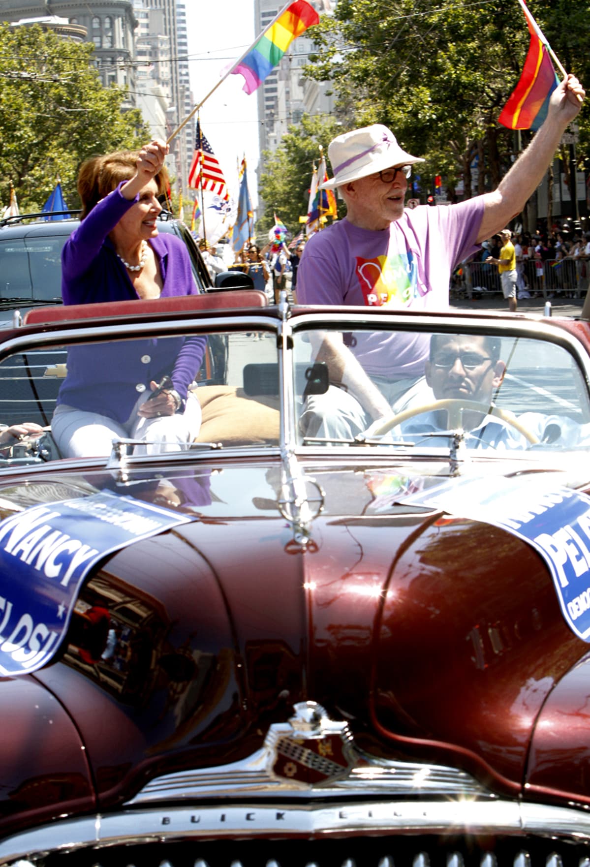Auton kyydissä paraatissa istuva Nancy Pelosi heiluttaa sateenkaarilippua.