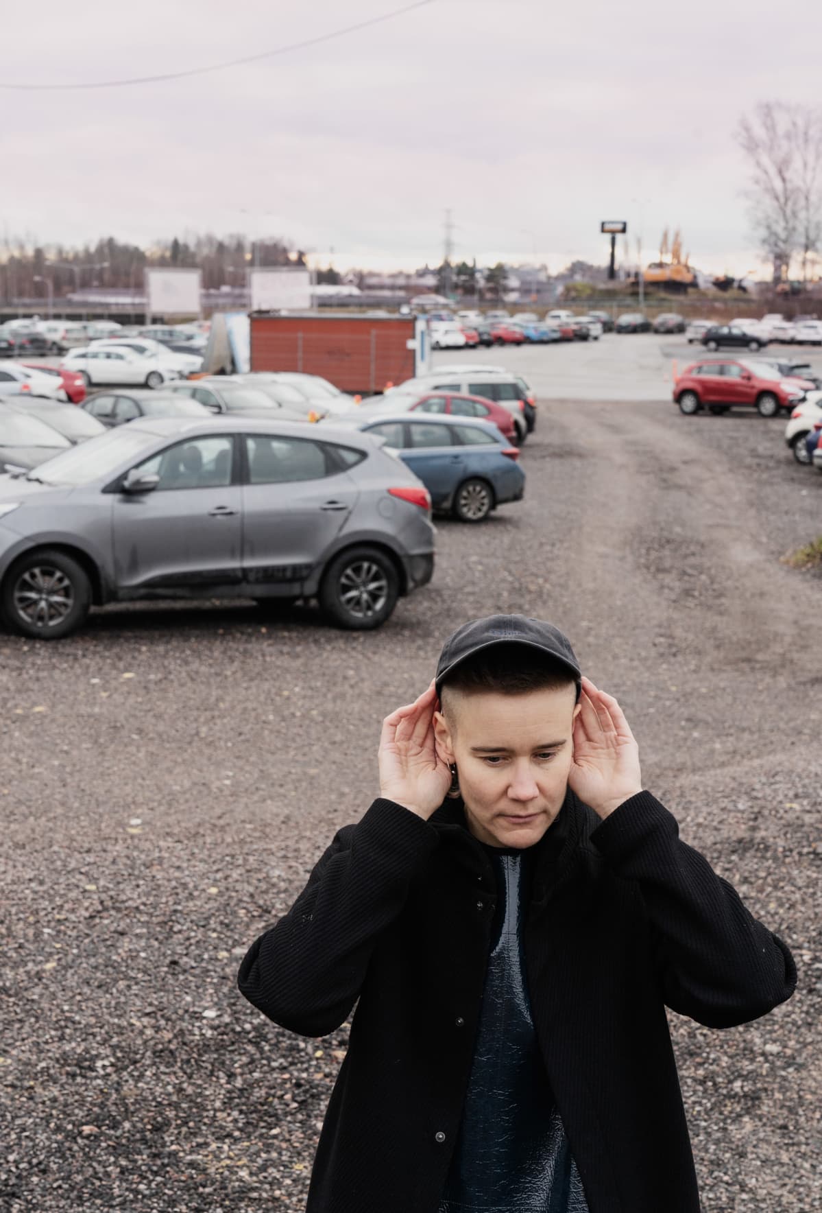 Emilia Kokko kuuntelee ympäristön ääniä parkkialueella lentokentän lähellä.
