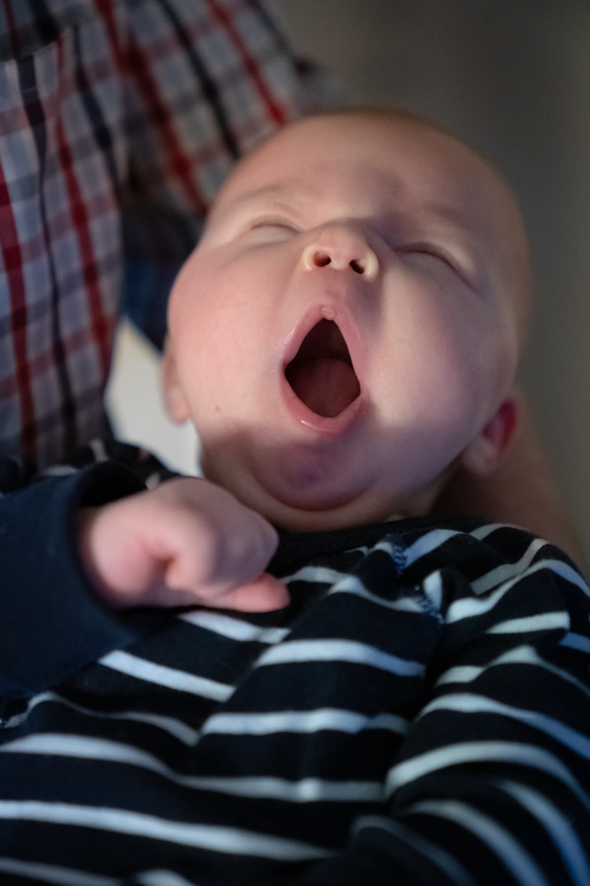Vauva haukottelee isän sylissä lähikuvassa.