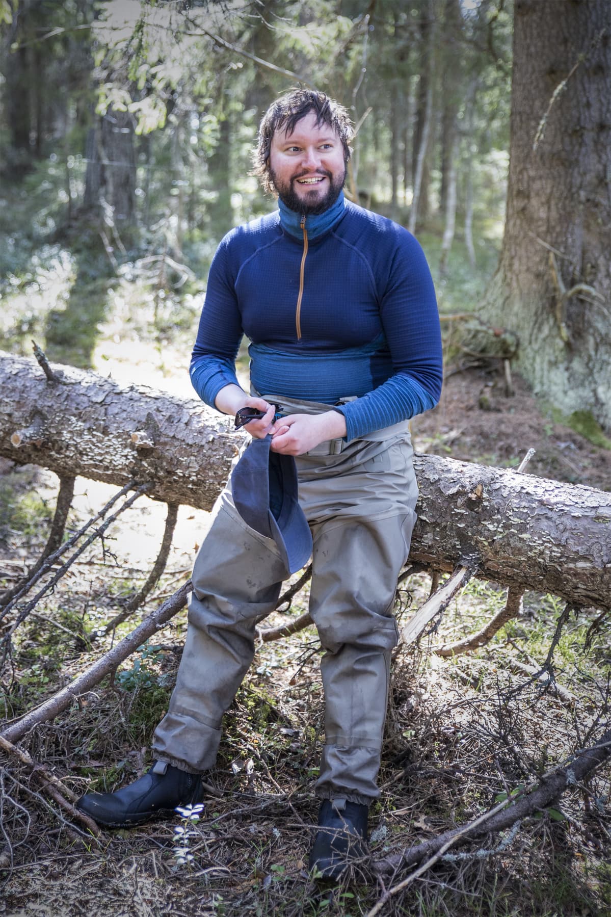 Mies nojaa kaatuneeseen puunrunkoon metsässä.